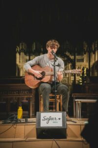 Trubadur som spelar på en gitarr och sjunger.